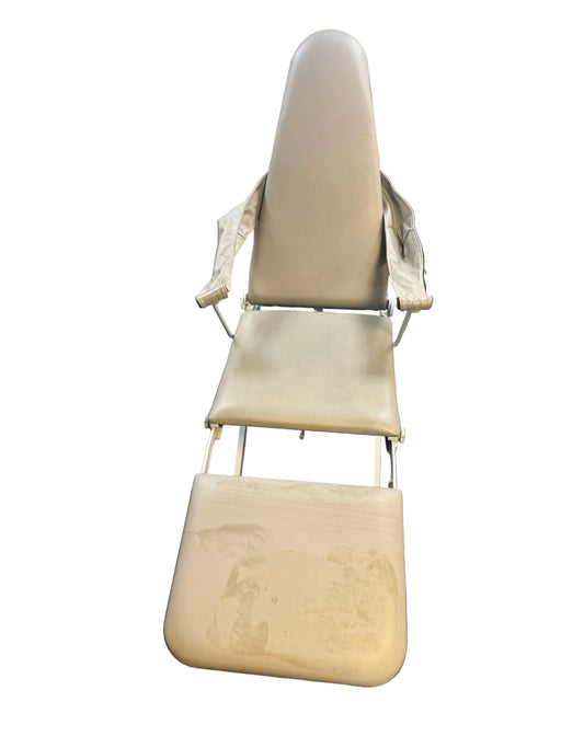 Beige massage chair on a gray floor with medical equipment in the background