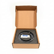 An open cardboard box containing a coiled gray cable with a white and blue connector, resting on a blue chair in a workshop setting.