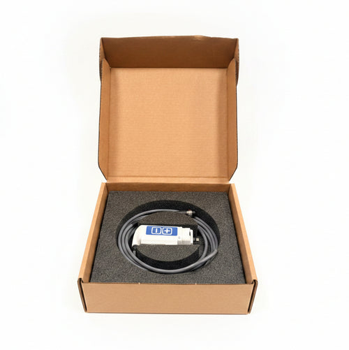 An open cardboard box containing a coiled gray cable with a white and blue connector, resting on a blue chair in a workshop setting.