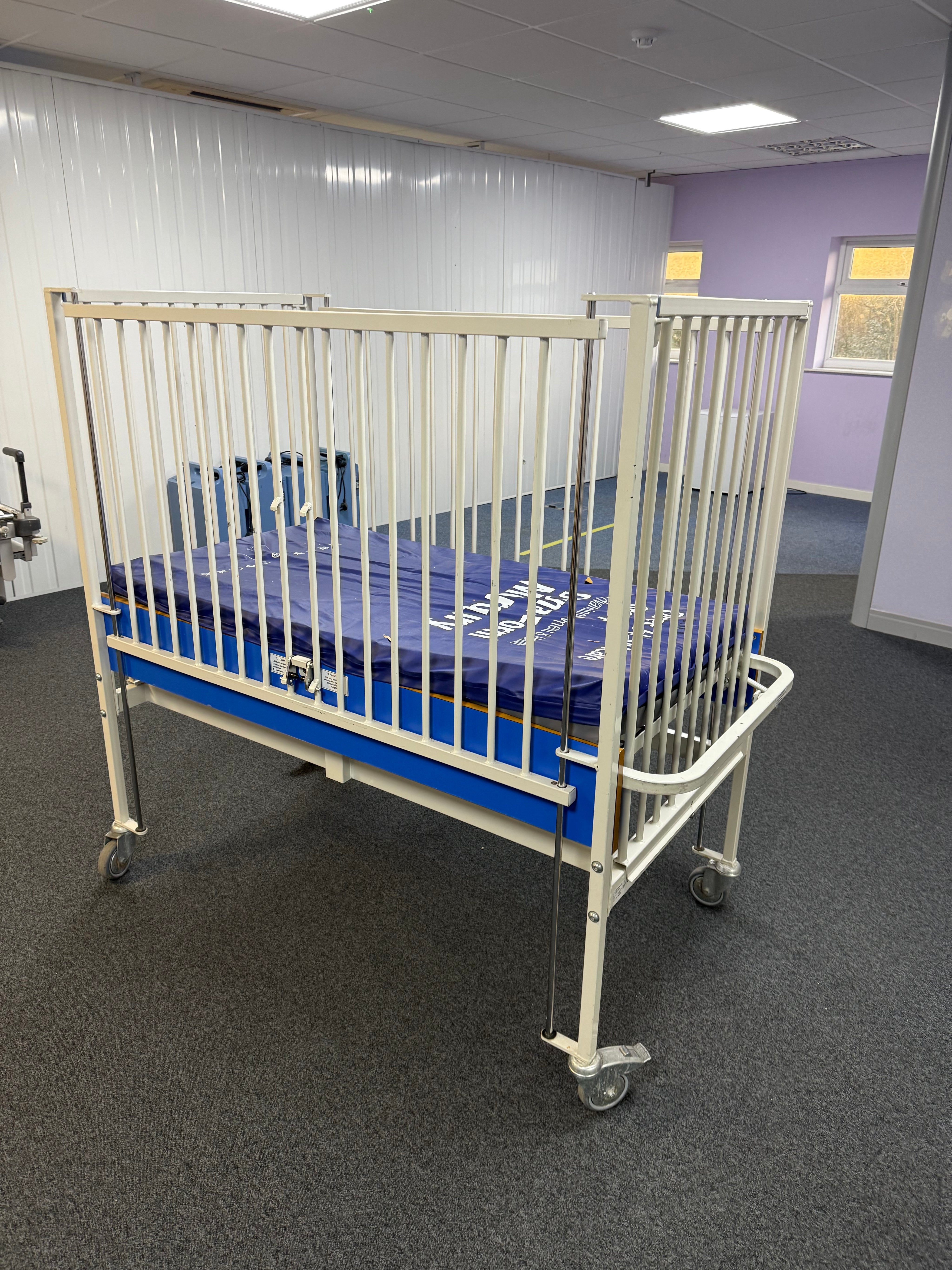 Angled view of ArjoHuntleigh Manual Infant Cot showing mattress space