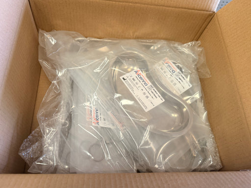 A packaged metal appliance part, likely a dishwasher component, sealed in clear plastic with a printed label, sitting inside an open brown cardboard box.