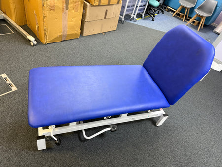 Side view of hydraulic patient couch with adjustable backrest and vinyl upholstery